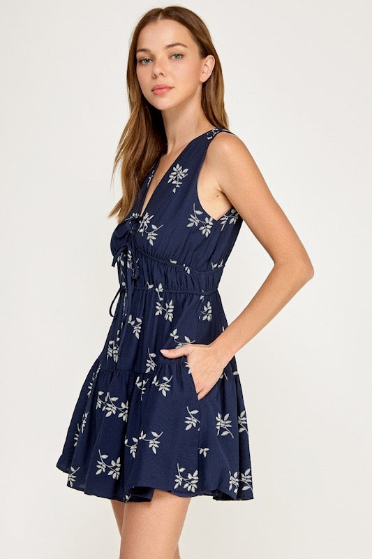 Woman wearing a navy blue dress with floral pattern on a white background