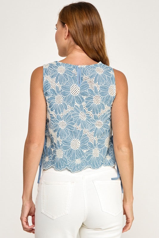 Woman wearing a blue floral sleeveless top on a white background