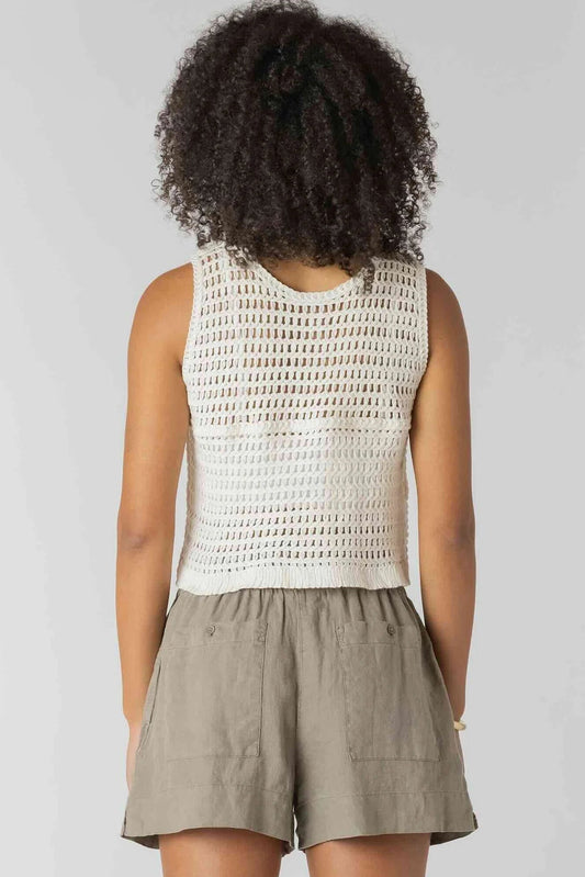 Person wearing a white sleeveless top and beige shorts on a plain background