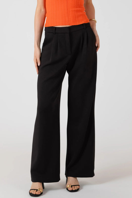 Person wearing black wide-leg pants and an orange top on a white background