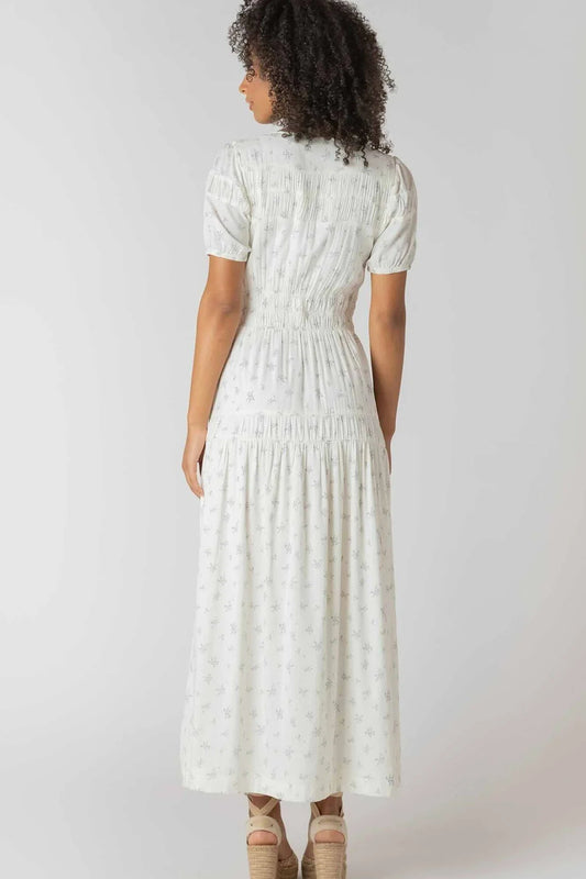 Woman wearing a white dress with a subtle pattern on a plain background
