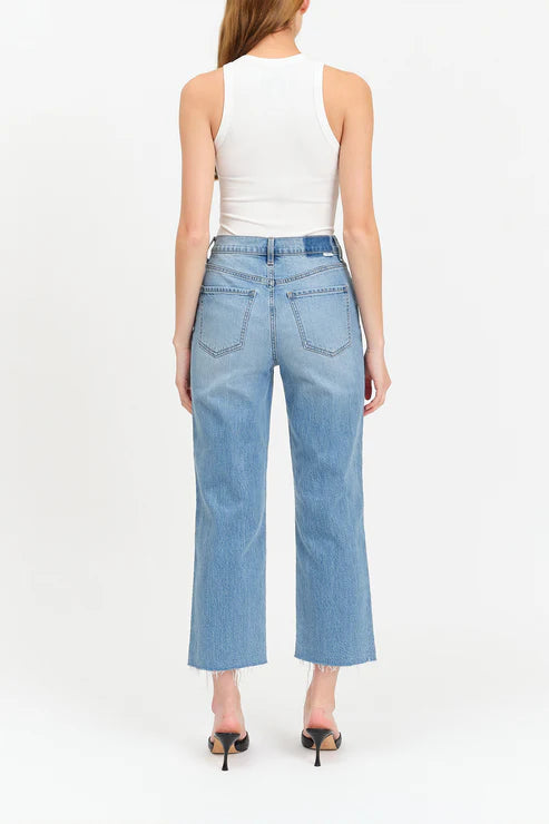 Woman wearing light blue jeans and a white top on a white background