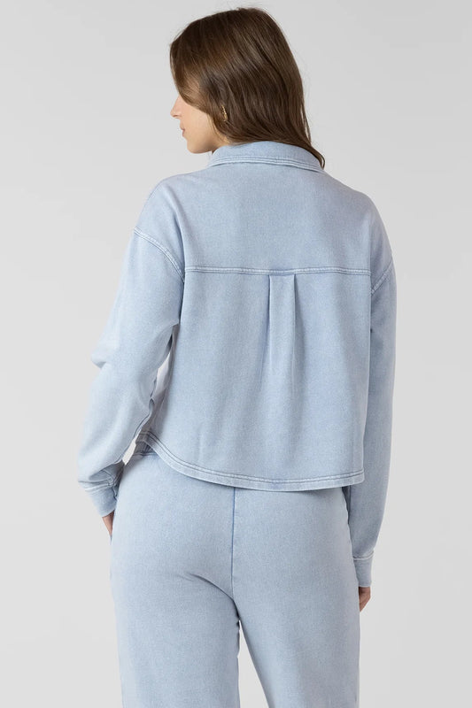 Woman wearing a light blue jacket and pants against a plain background