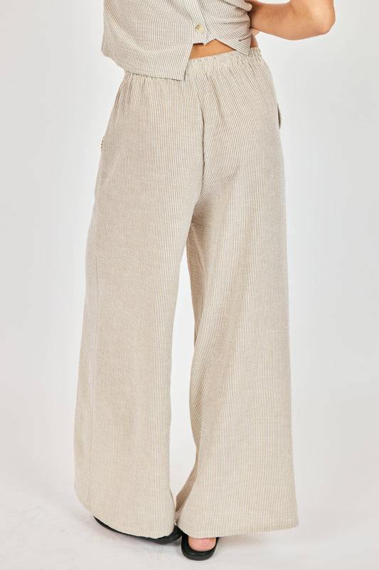 Beige ribbed wide-leg pants worn by a person on a white background