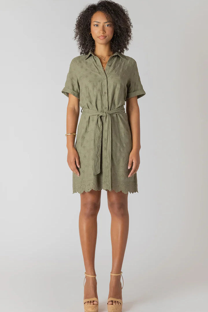 Woman wearing a green dress with a belt on a white background