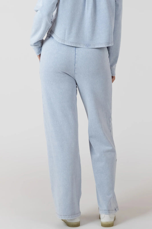 Light blue outfit with pants and a top on a plain background