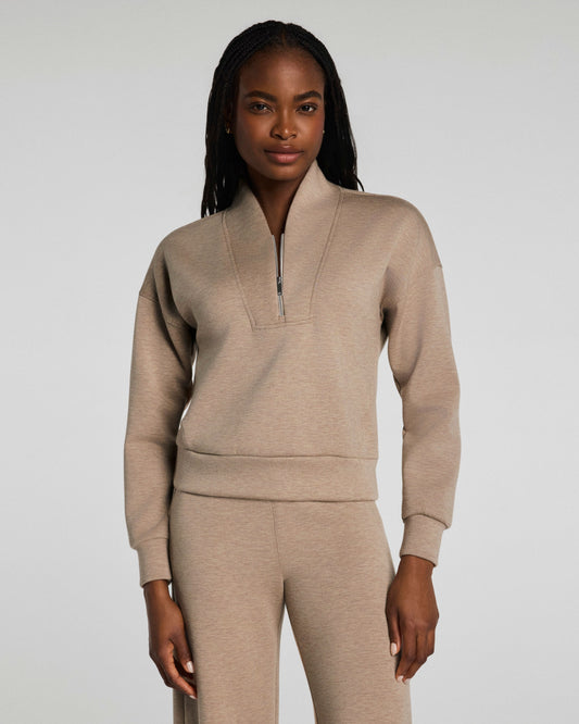 Woman wearing a beige tracksuit against a plain background