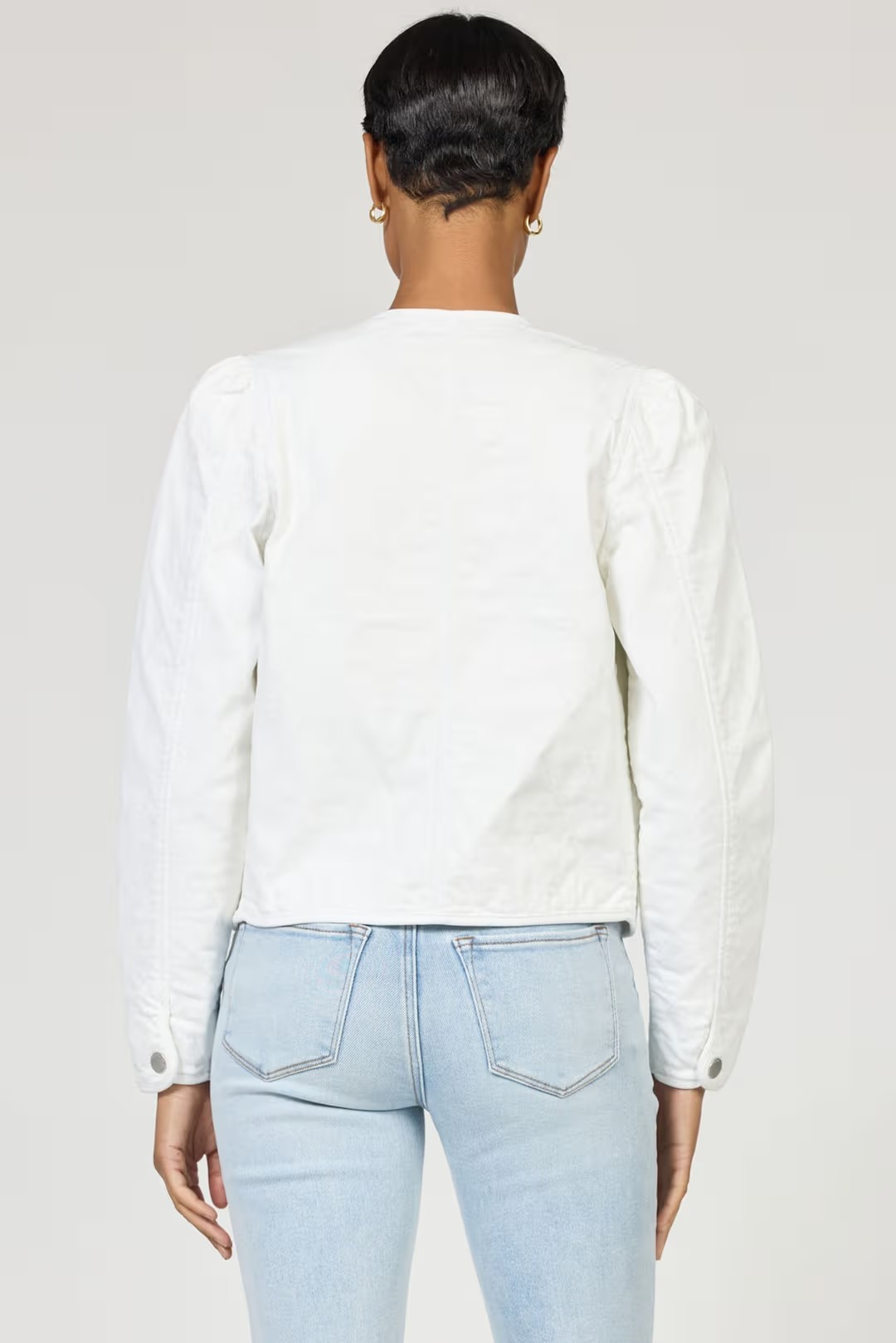 Person wearing a white shirt and light blue jeans on a plain background