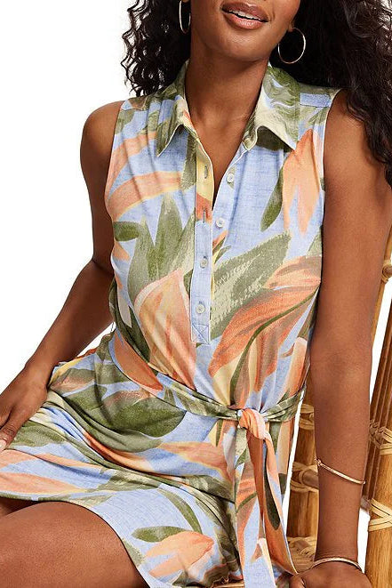 Woman wearing a colorful floral dress sitting on a wicker chair.