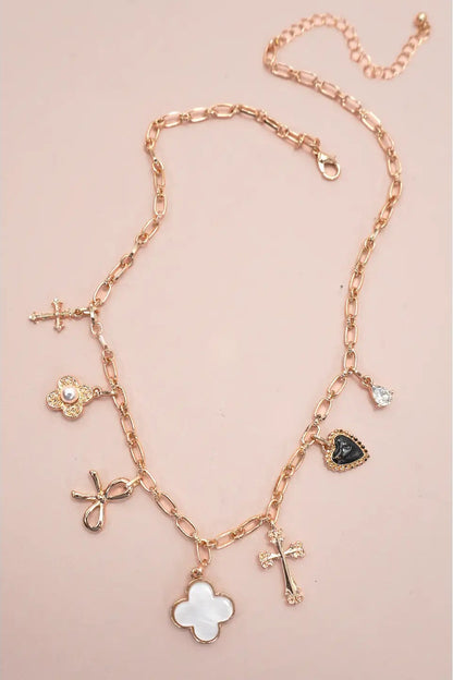 Rose gold necklace with various charms on a pink background