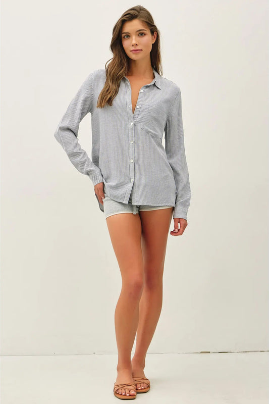 Woman wearing a light gray button-up shirt and shorts on a white background