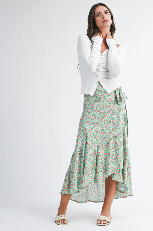 Woman wearing a white top and green floral skirt on a white background
