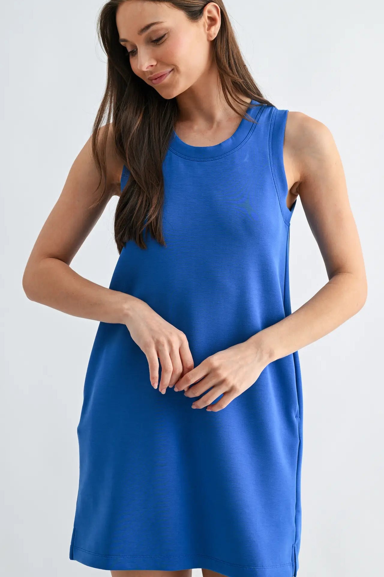 Woman wearing a blue sleeveless dress against a light gray background