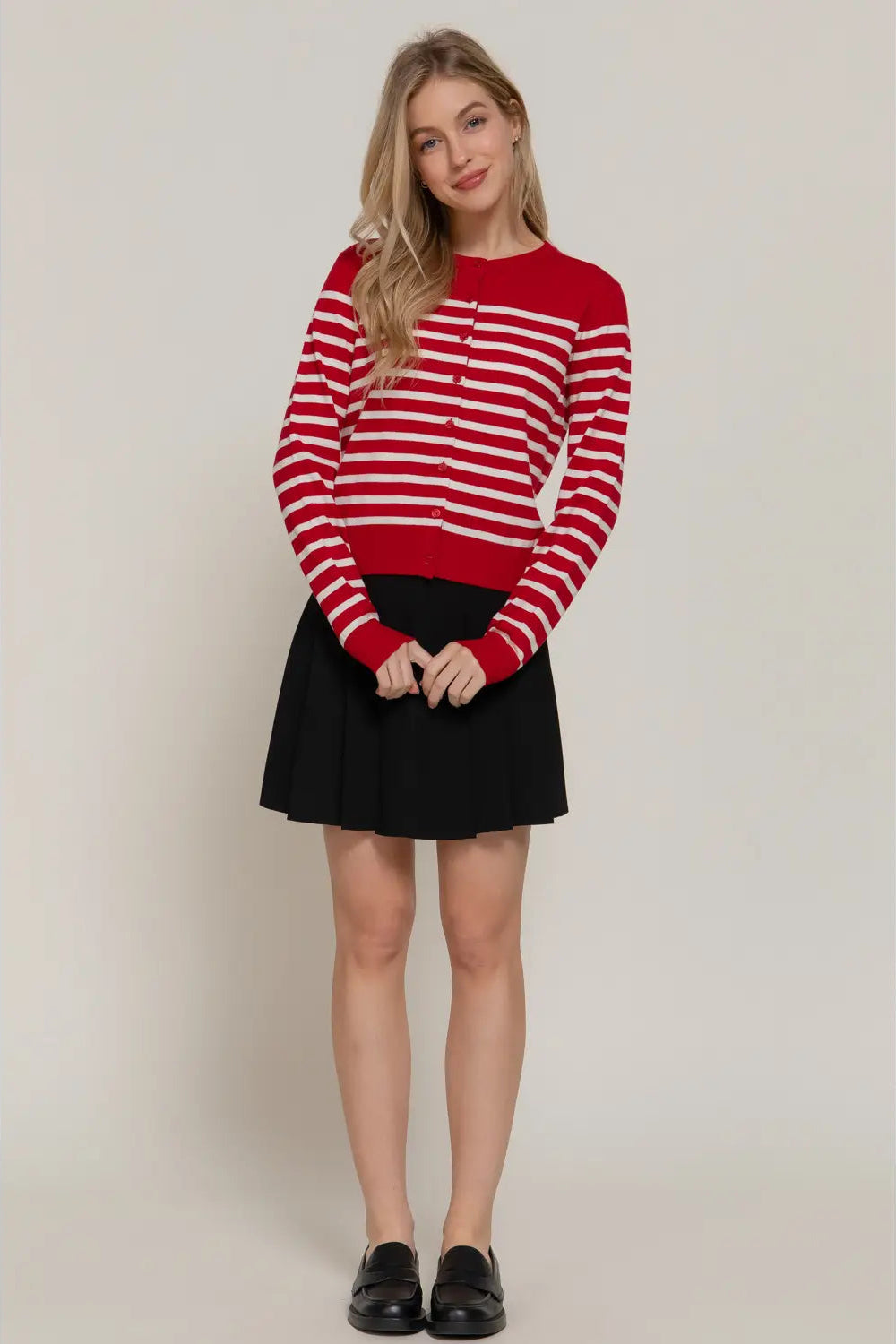 Woman wearing a red and white striped sweater with a black skirt on a plain background