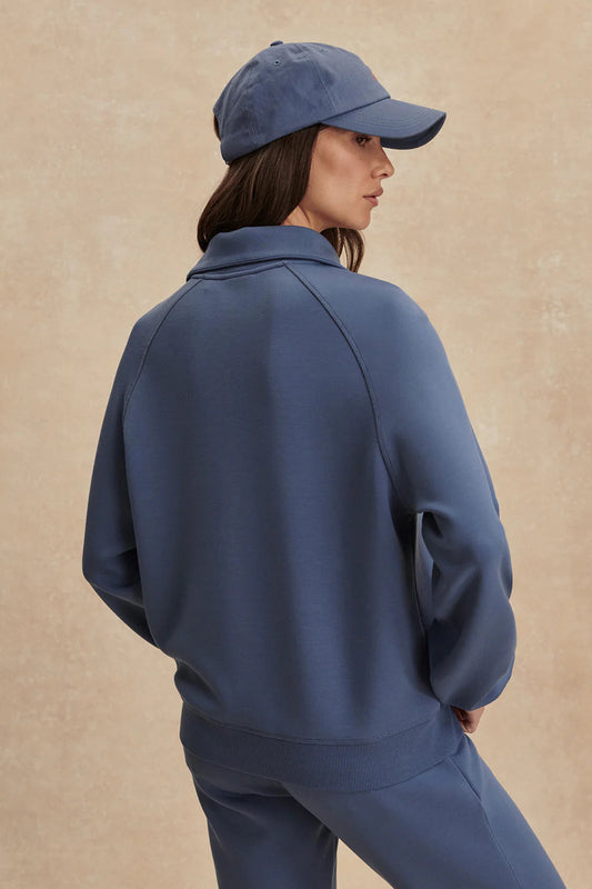 Person wearing a blue tracksuit and cap on a beige background