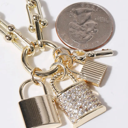 Gold padlock charm with a quarter for scale on a white background