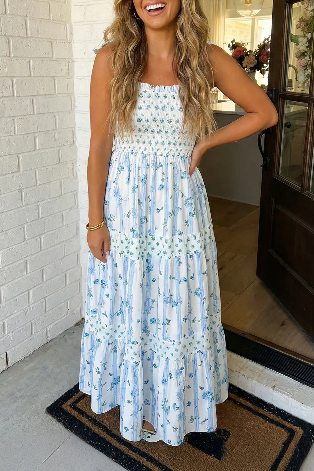 Woman wearing a floral dress standing in a doorway.