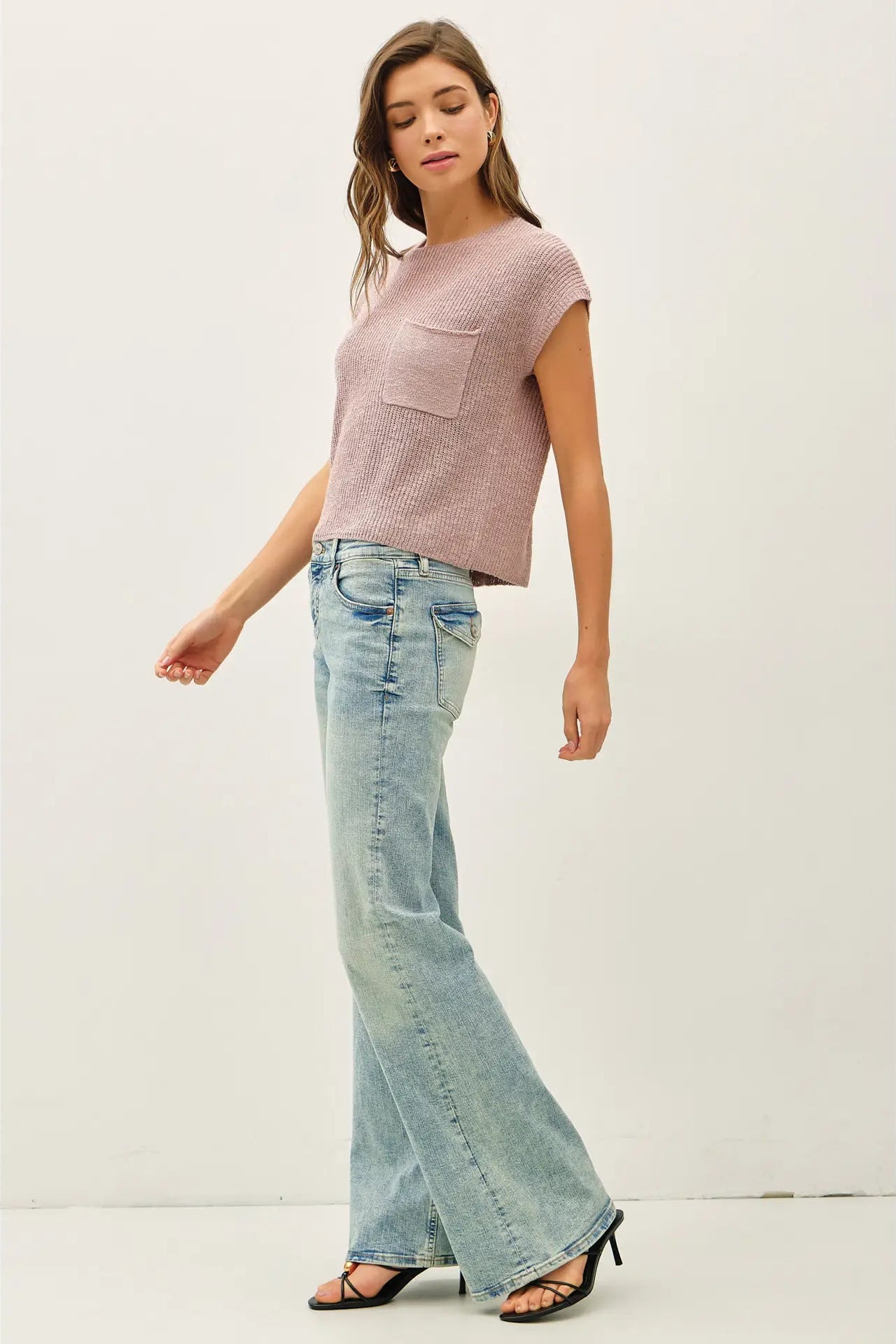 Woman wearing a pink top and light blue jeans on a white background