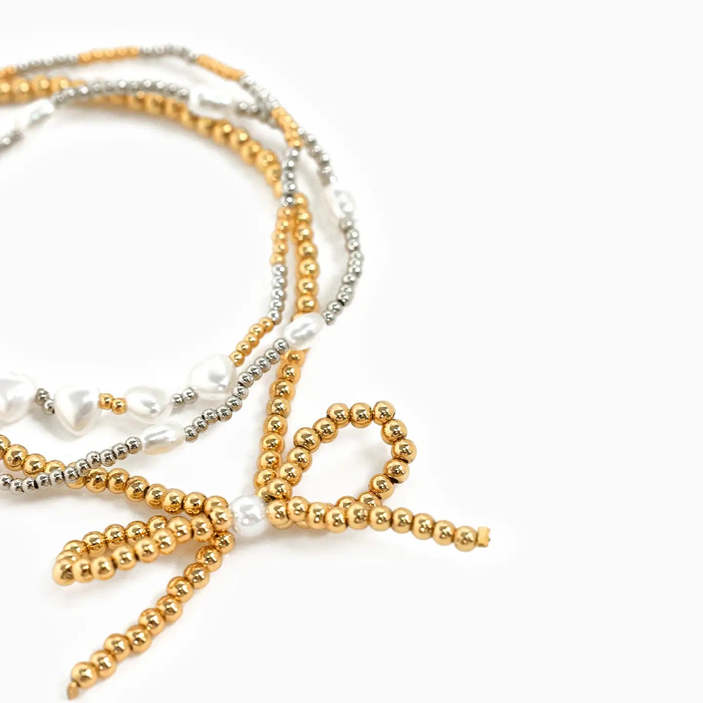 Set of gold, silver, and pearl beaded bracelets on a white background