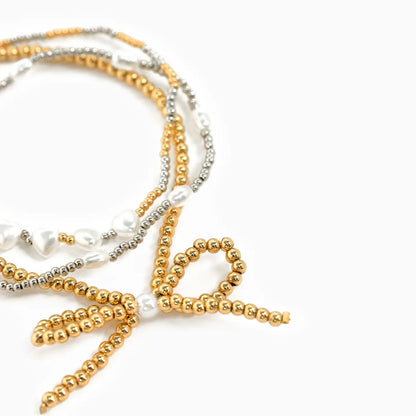 Set of gold, silver, and pearl beaded bracelets on a white background