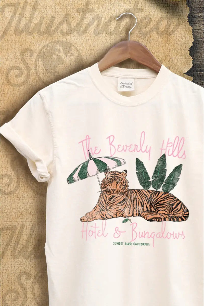 White t-shirt with tiger graphic and text on a hanger against a textured wall.