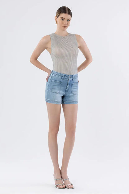 Woman wearing a gray sleeveless top and light blue denim shorts on a white background