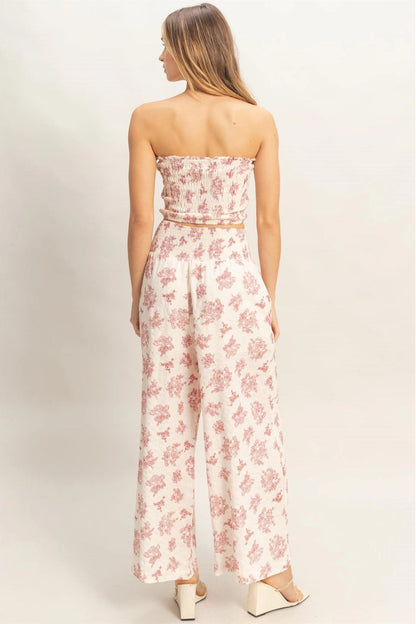 Woman wearing a strapless floral jumpsuit on a plain background
