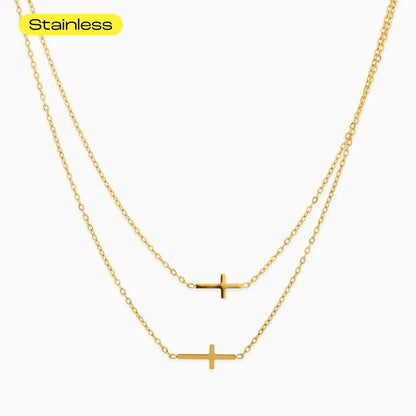 Gold cross necklace on a white background with 'Stainless' text above.