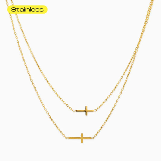 Gold cross necklace on a white background with 'Stainless' text above.