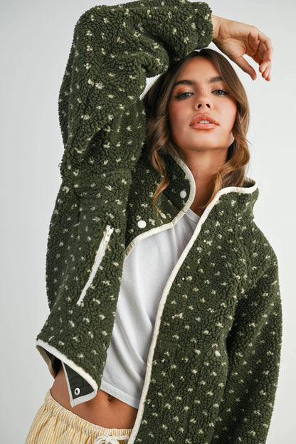 Woman wearing a green fleece jacket with a white interior on a plain background