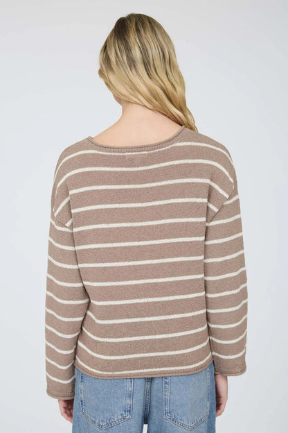 Person wearing a striped sweater and jeans on a plain background