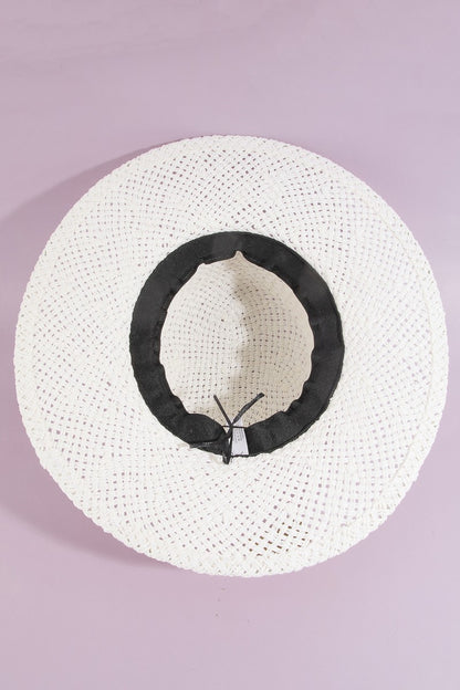 White straw hat with black band on a light purple background