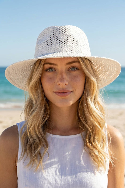 Woman wearing a white sun hat on a beach with clear blue sky