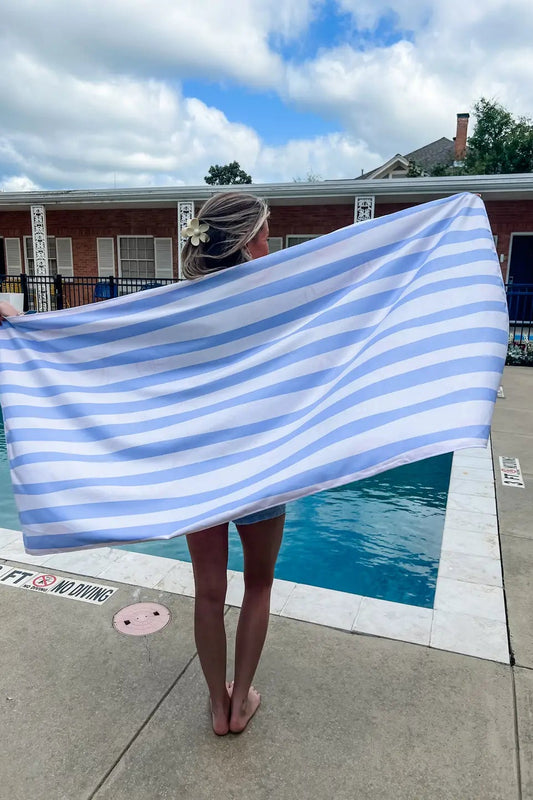 Person holding a blue and white striped towel by a pool