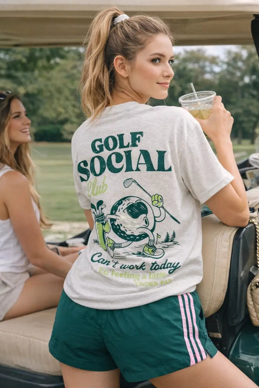 woman by golf cart wearing golf social tee with green shorts