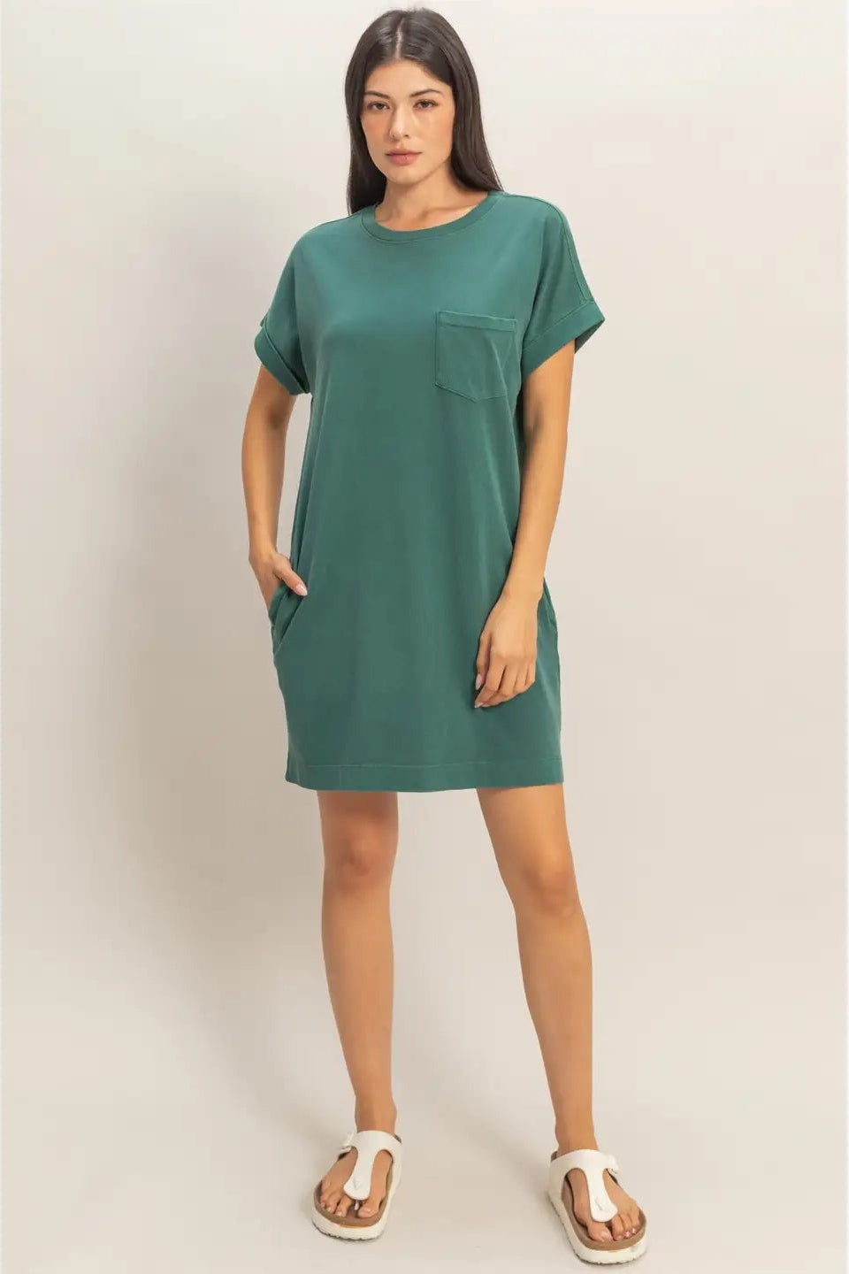 Woman wearing a green dress with a pocket on a plain background