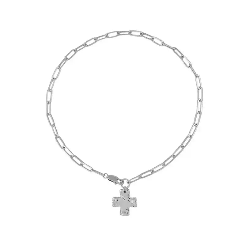 A silver paperclip chain bracelet with a small cross pendant, displayed on a clean white background.
