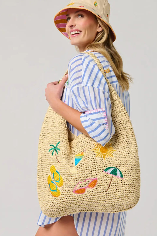 Woman holding a straw bag with summer-themed designs against a light gray background