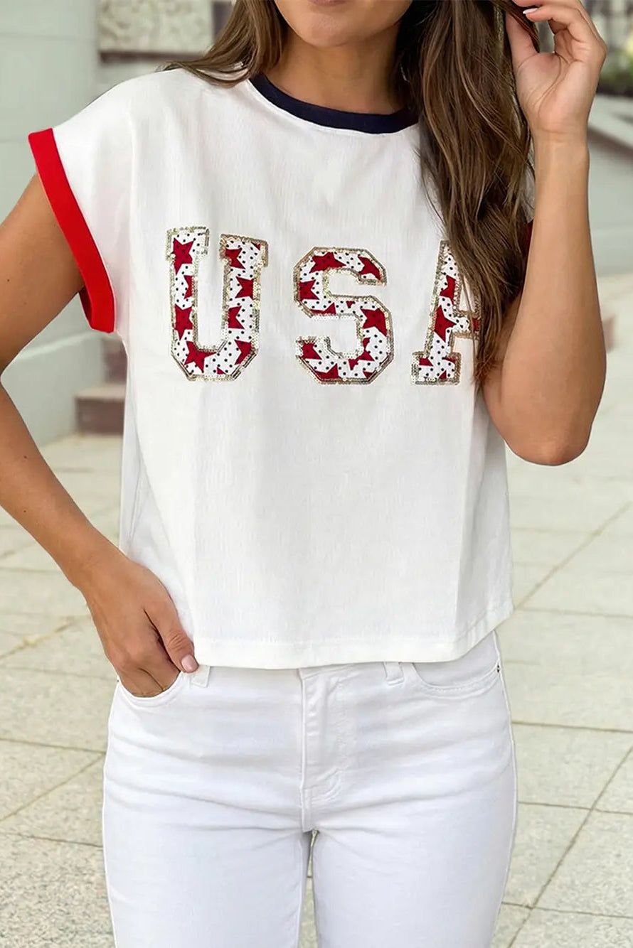 Person wearing a white t-shirt with 'USA' printed in red and blue, standing on a tiled floor.