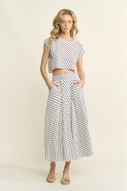 Woman wearing a polka dot top and skirt set on a beige background