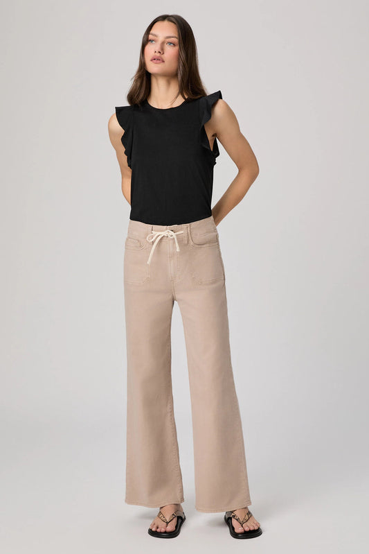 Woman wearing a black top and beige pants on a white background