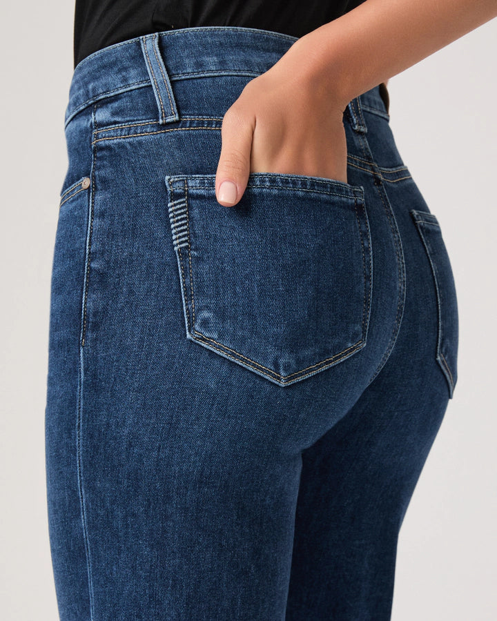 Close-up of blue jeans with a hand in the pocket on a light gray background