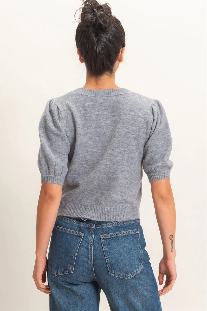 Person wearing a gray sweater and blue jeans on a plain background