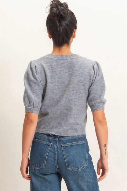 Person wearing a gray sweater and blue jeans on a plain background