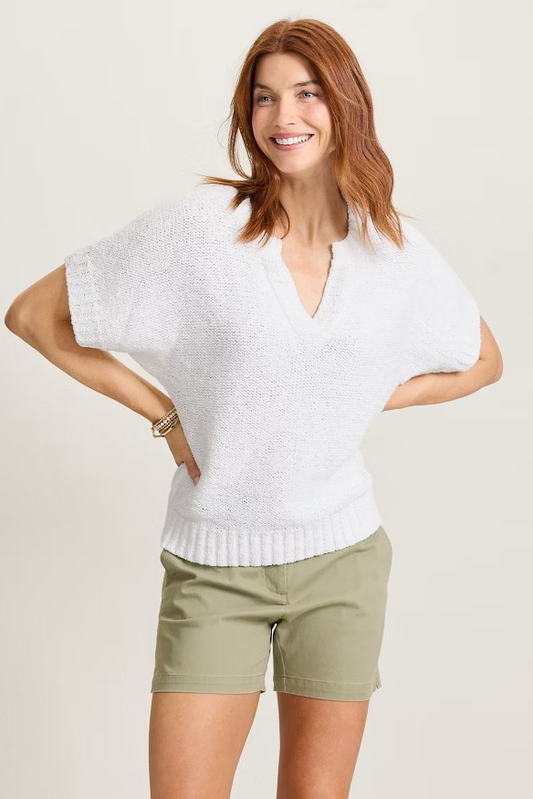 Woman wearing a white sleeveless top and green shorts on a plain background