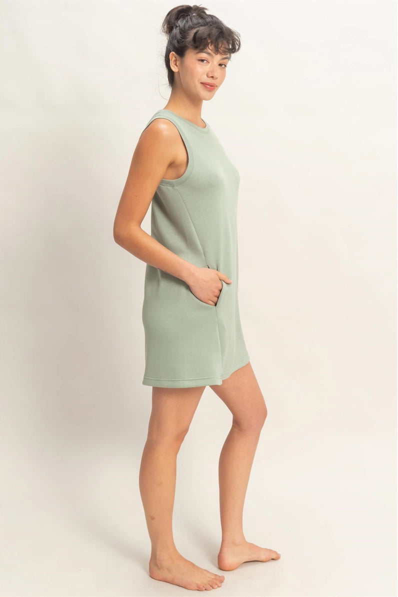 Woman wearing a light green sleeveless dress against a plain background