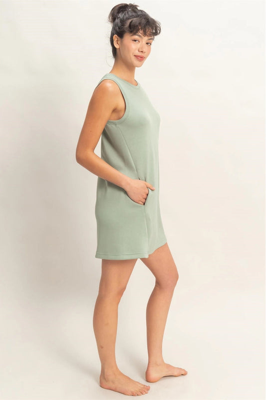 Woman wearing a light green sleeveless dress against a plain background