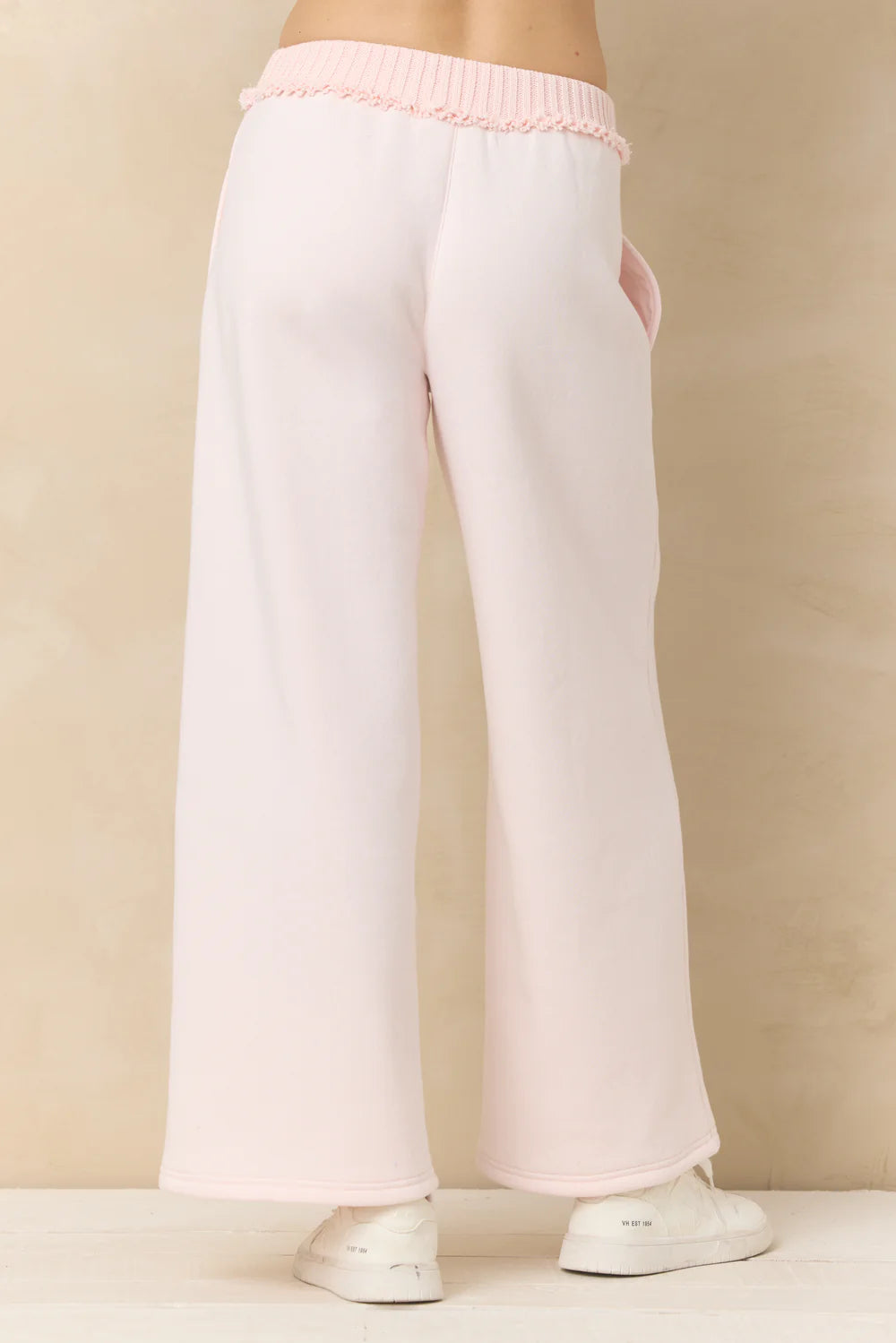 White lounge pants with pink trim on a beige background
