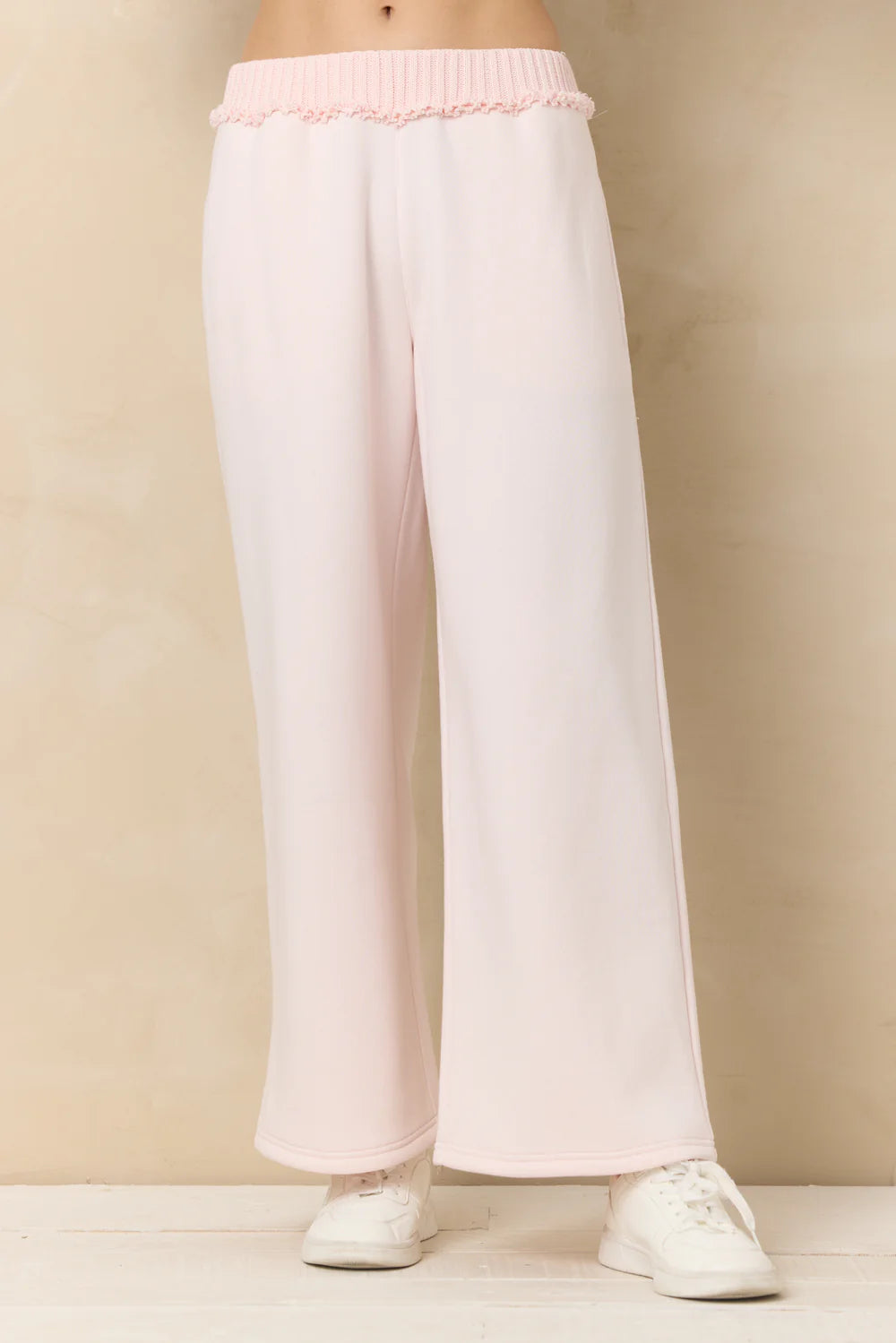 White pants with pink waistband on a beige background