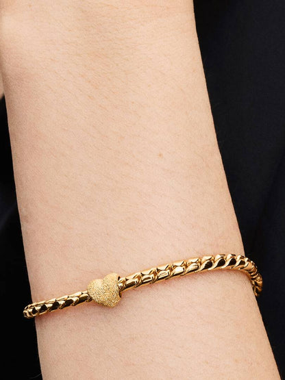Gold bracelet on a wrist with a black background